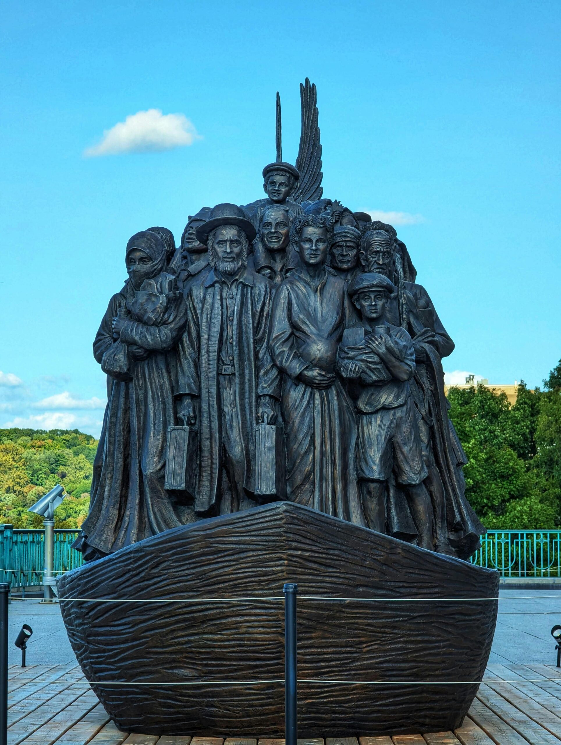 Bronze statue depicting diverse immigrant group outdoors, symbolizes hope and journey.